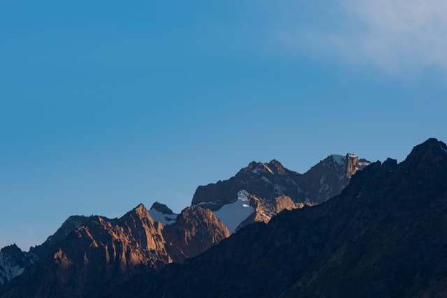 雪山在蓝天映衬下，山峰被阳光照亮。