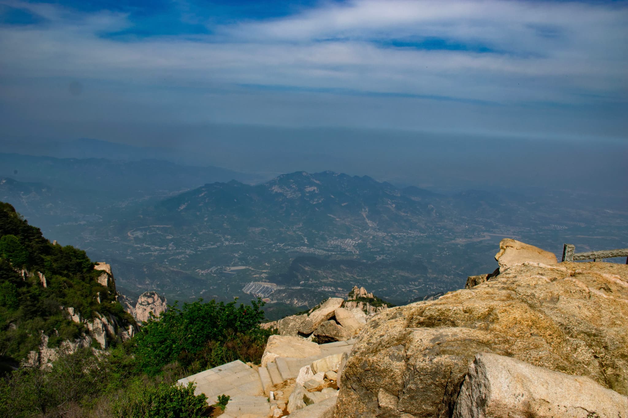 山峦起伏，远眺城市，蓝天白云，岩石前景。