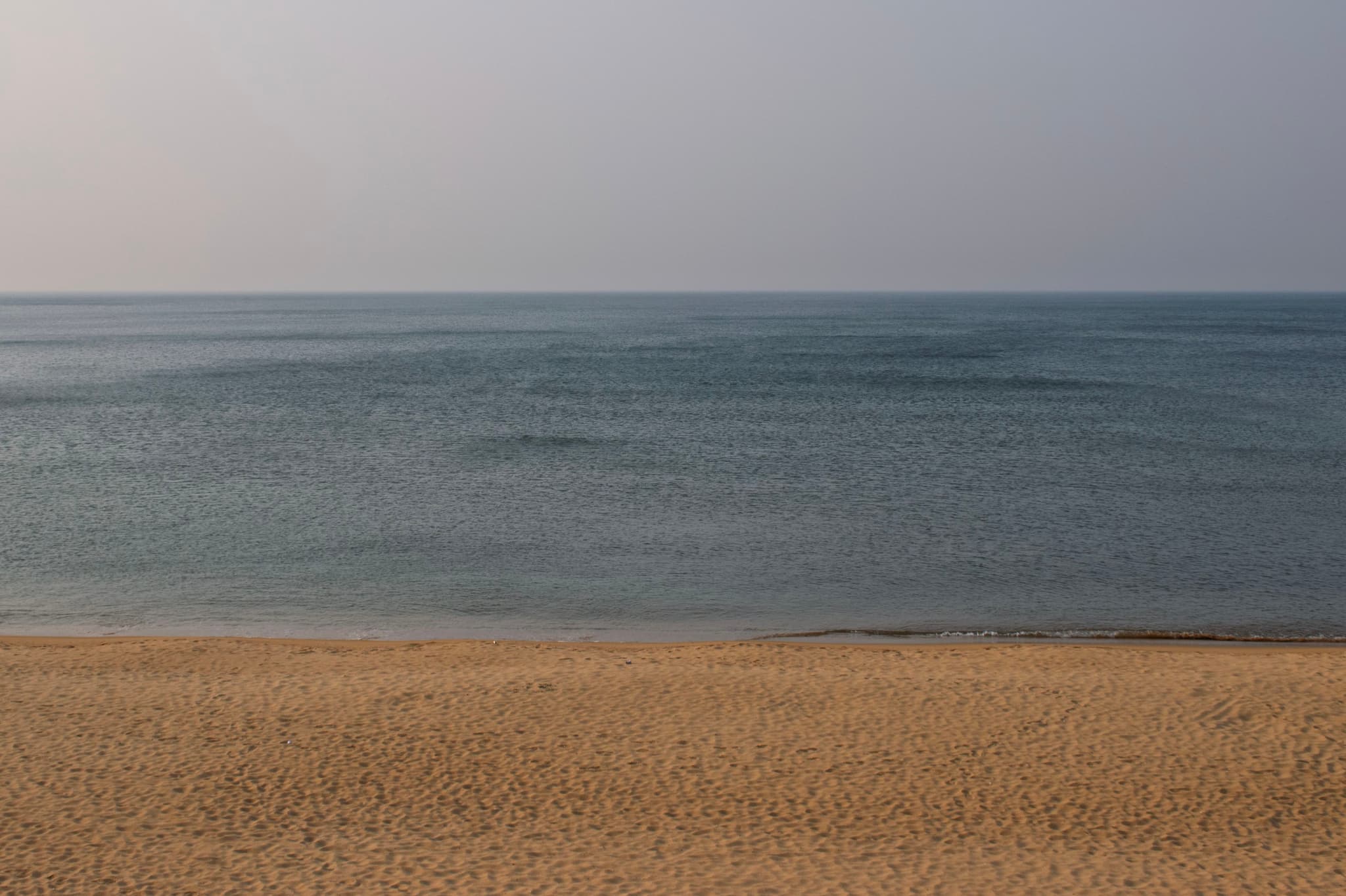 沙滩与大海相接，海水平静，天空晴朗。