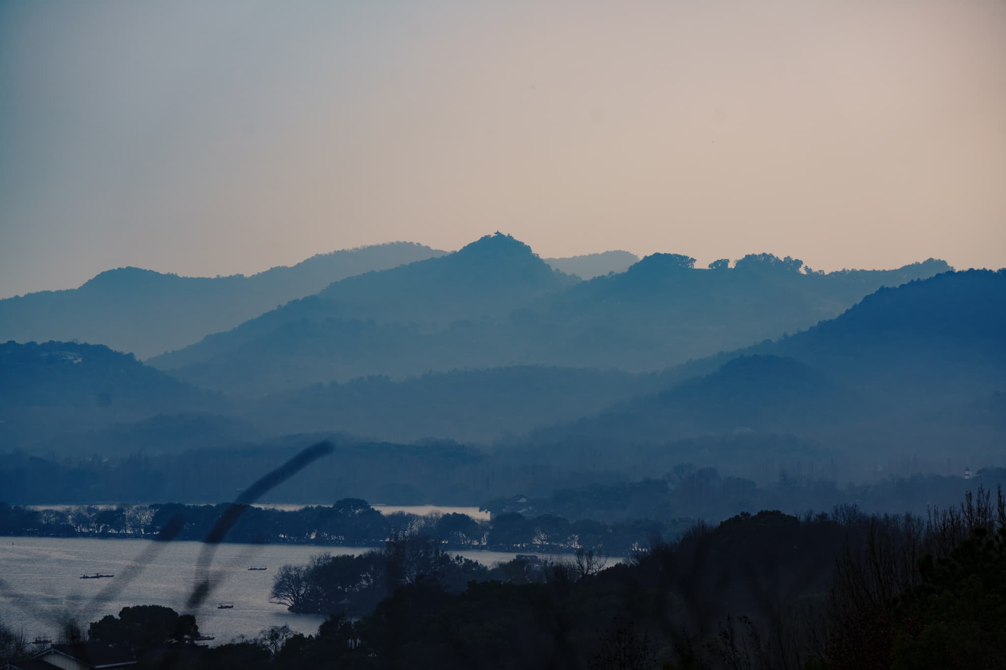 层叠的山峦在薄雾中若隐若现，远处的天空呈现出柔和的渐变色调，营造出宁静的氛围。