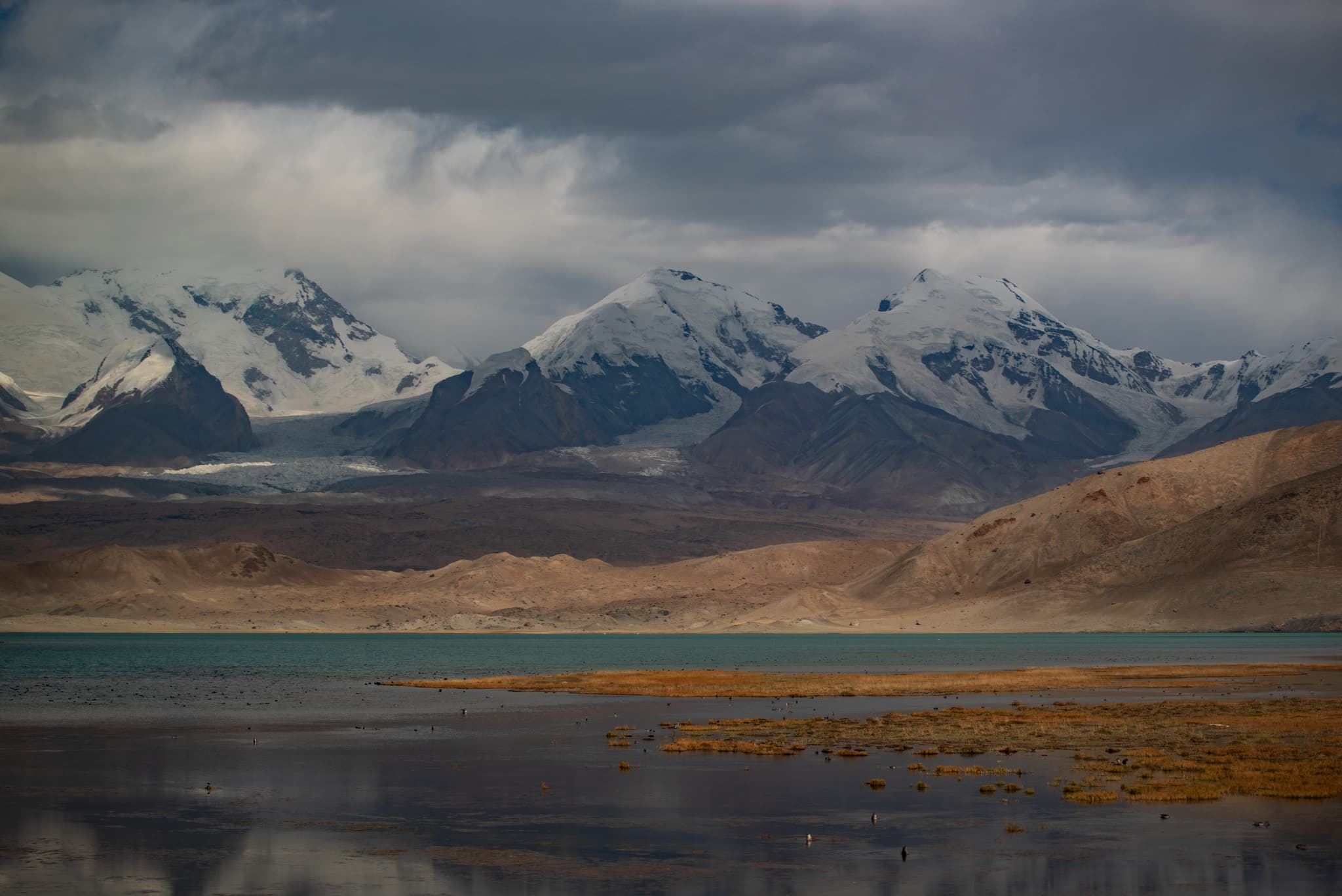 雪山环绕的湖泊，湖面倒映着山峰和天空，景色壮丽。