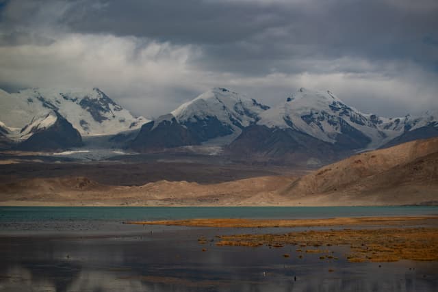 雪山环绕的湖泊，湖面倒映着山峰和天空，景色壮丽。