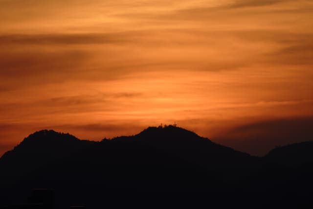 夕阳下的山峦剪影，天空呈现出橙色和金色的渐变。